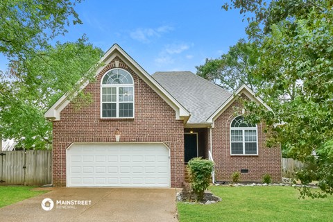 the front of a brick house with a white garage door
