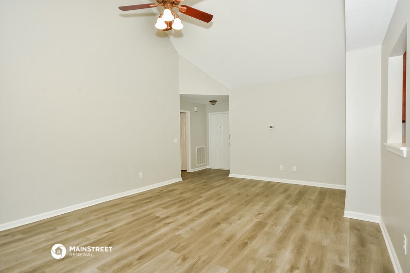 the living room and dining room with hardwood floors and a ceiling fan