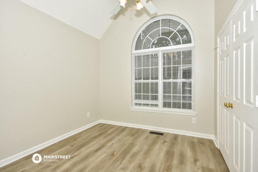 the living room of a home with a large window and wooden floors