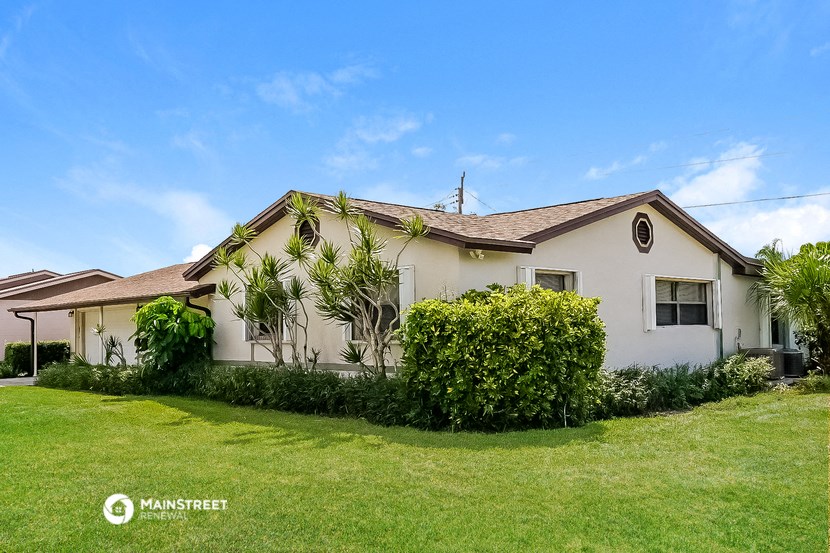 a white house with a lawn and plants in front of it