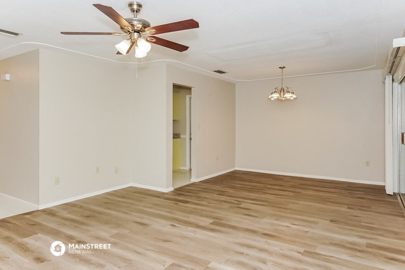 the living room of an empty house with a ceiling fan