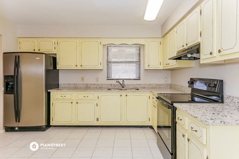 a kitchen with yellow cabinets and a stove and refrigerator