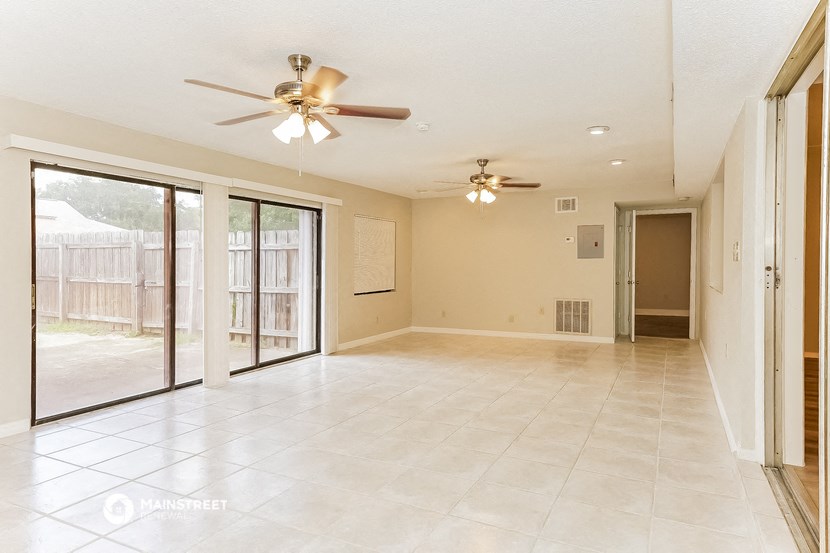 an empty living room with a ceiling fan and sliding glass doors
