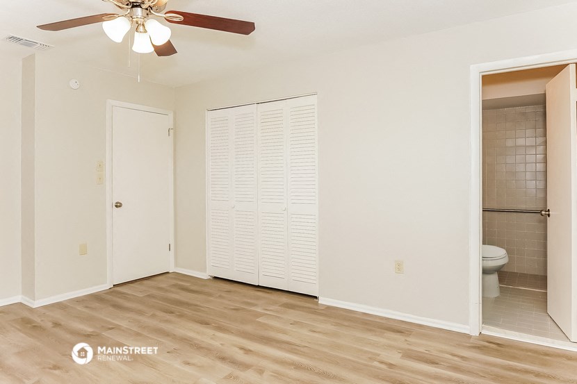 a living room with a ceiling fan and a door to a bathroom
