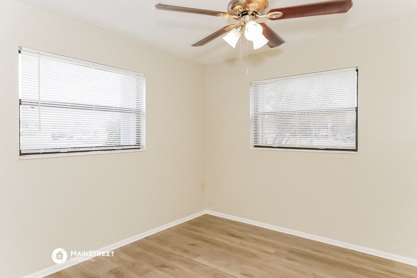 a bedroom with a ceiling fan and two windows