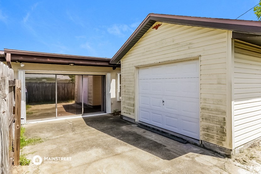 a small white garage with a white garage door and a driveway