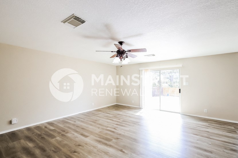 a living room with white walls and a ceiling fan