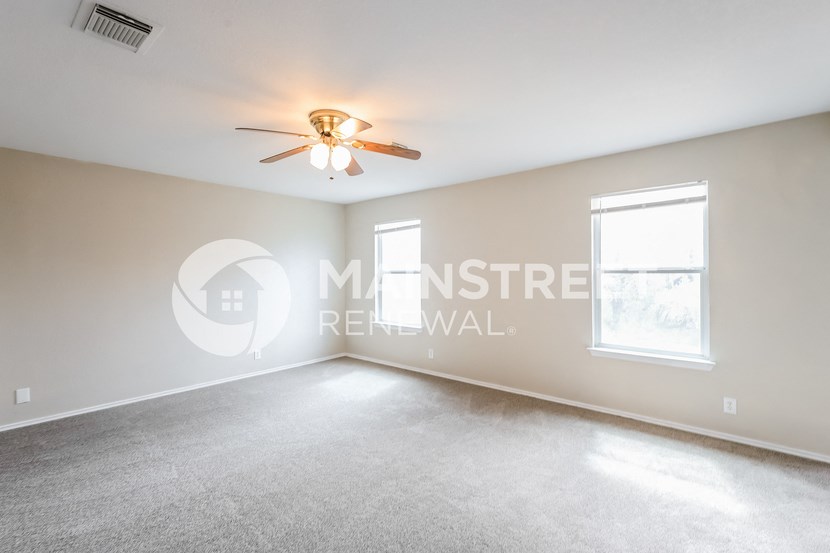 two windows in a room with carpet and a ceiling fan