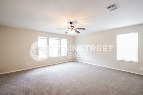 a living room with carpet and a ceiling fan