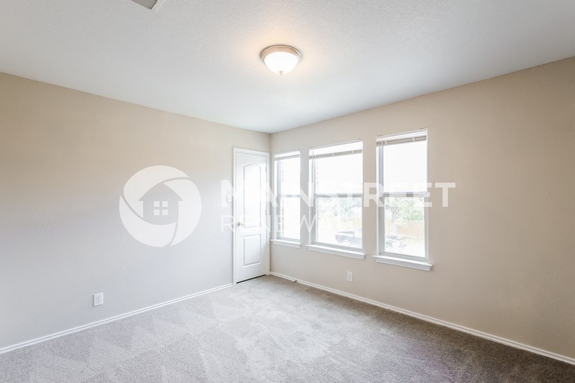 the spacious living room with large windows and white carpeting