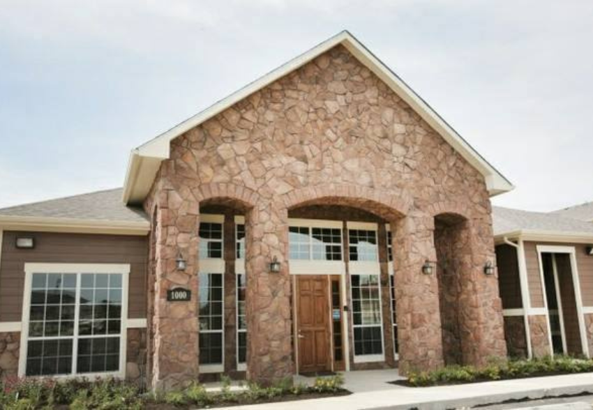 the front of a stone building with wood doors and windows