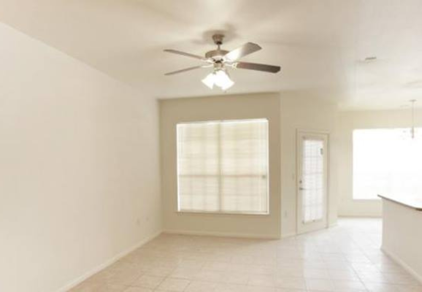 an empty living room with a ceiling fan