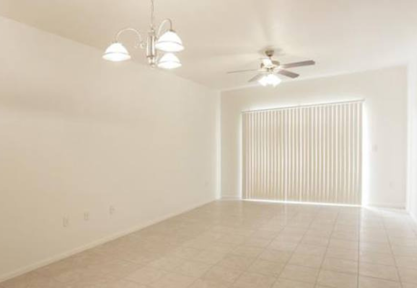 an empty living room with a ceiling fan
