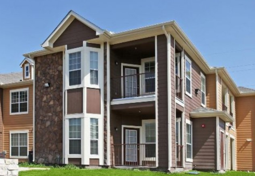 an apartment building with balconies and a stone wall