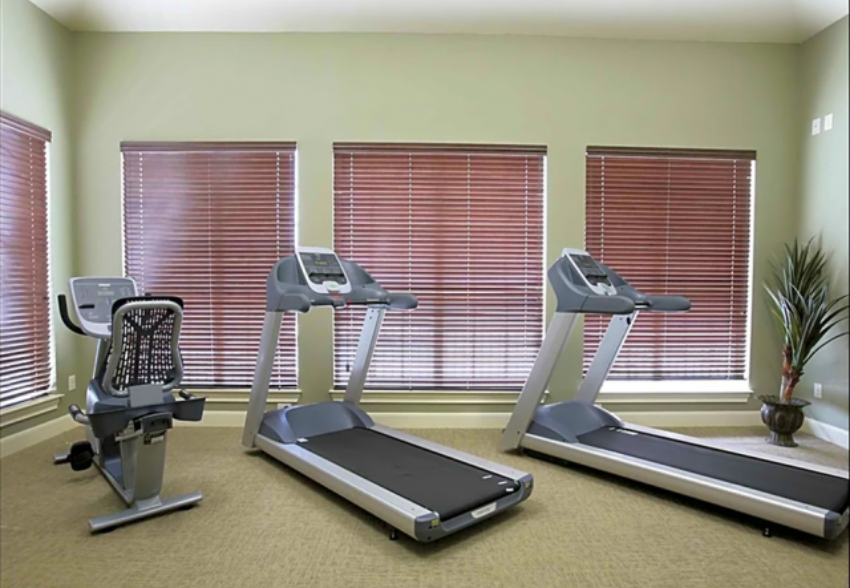two treadmills in a gym with windows blinds