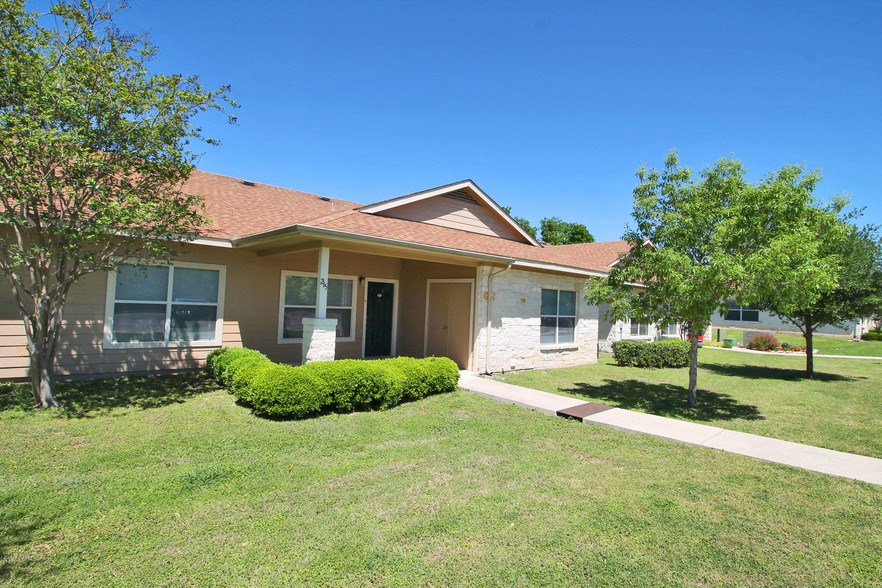 the front of a house with a lawn and trees