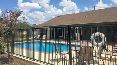 a house with a swimming pool behind a black fence