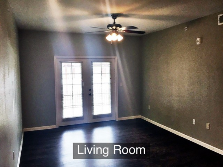 an empty living room with gray walls and a ceiling fan