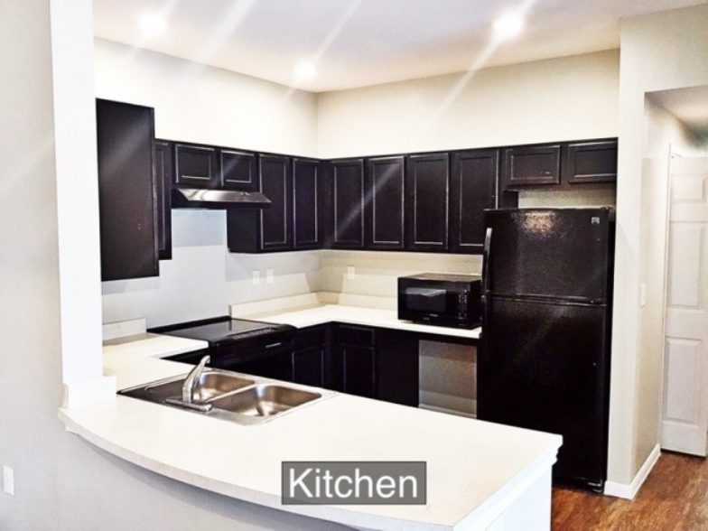 an empty kitchen with black appliances and white counter tops