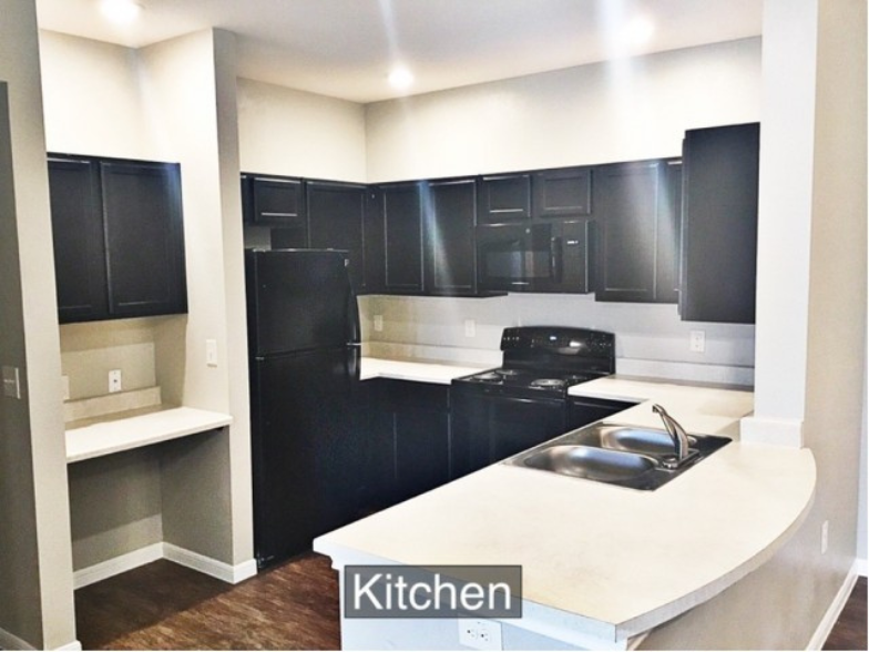 a kitchen with black cabinets and white counter tops and a black stove and a sink