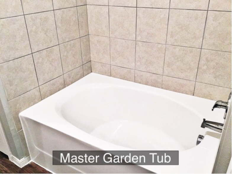 a white tub in a tiled bathroom with master garden tub