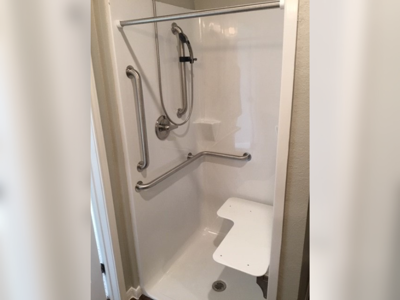 a shower with grab bars in a hotel bathroom