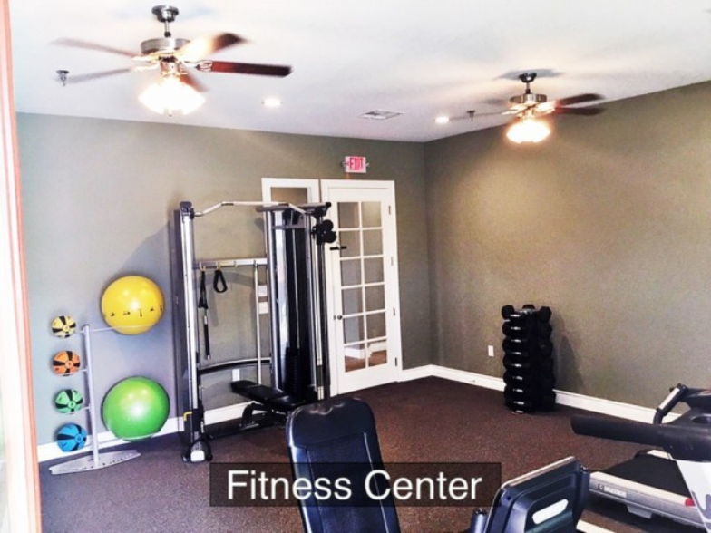 a gym with weights and a fitness center with a ceiling fan