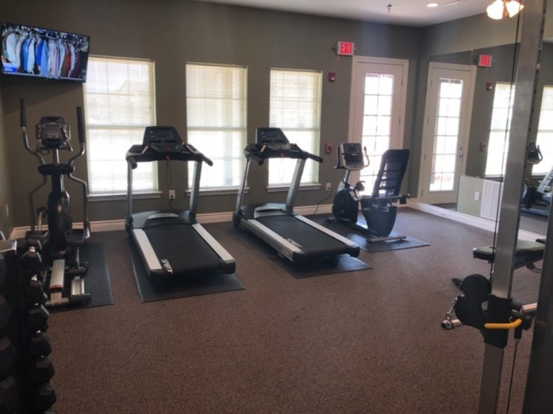 a gym with cardio equipment in a room with windows