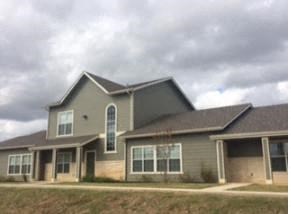 a large house with a brown roof and a cloudy sky