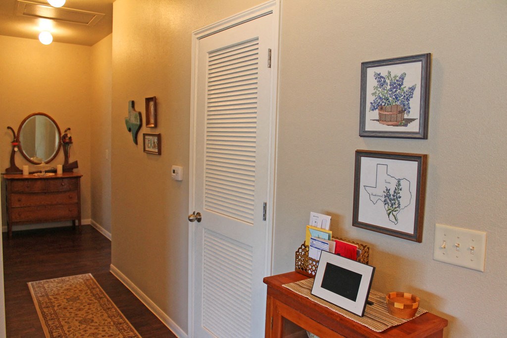 a living room with a white door and a desk with a laptop and pictures
