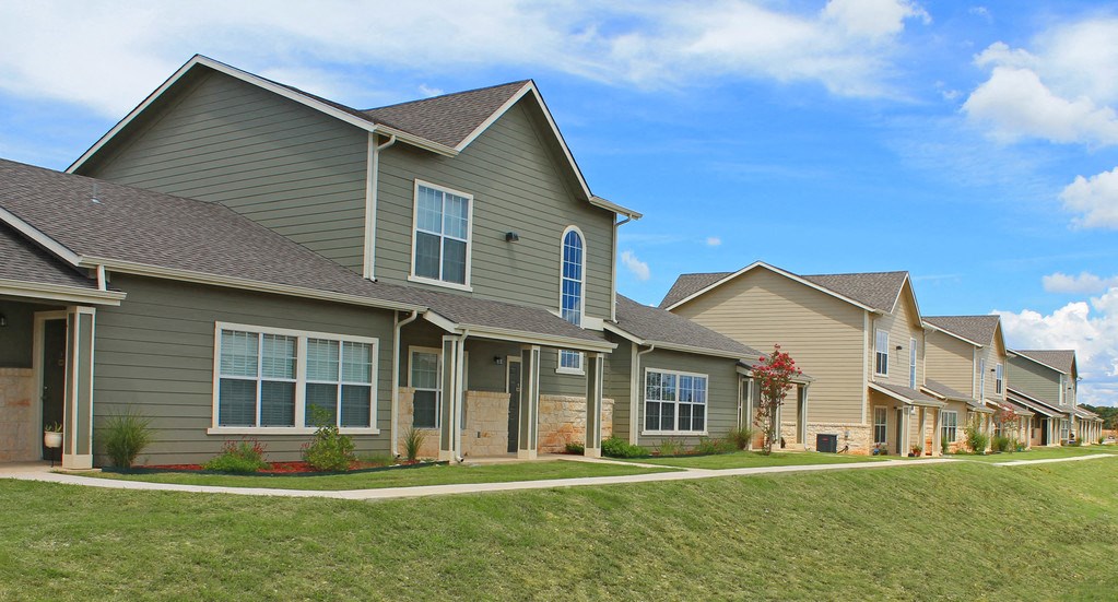 a row of houses on the side of a green lawn