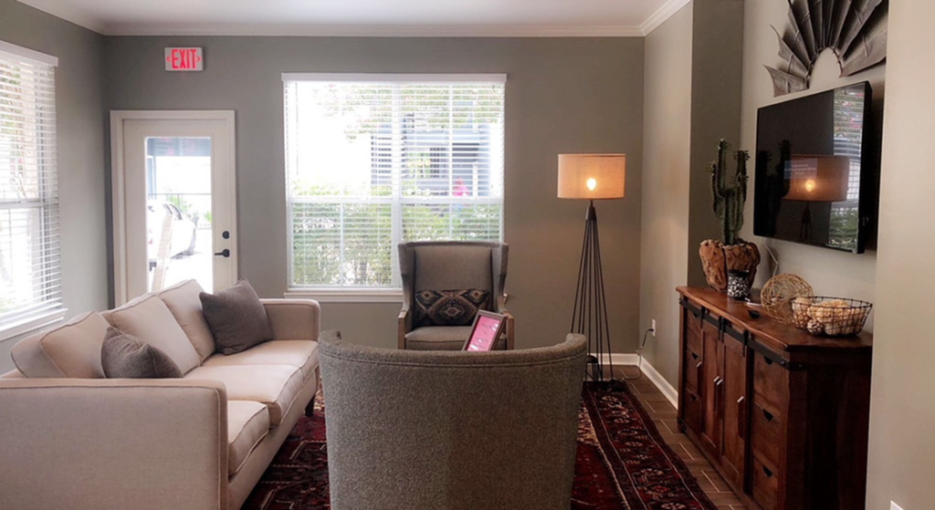 a living room with a couch and a chair and a window