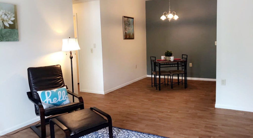 an empty living room with a chair and a dining room table
