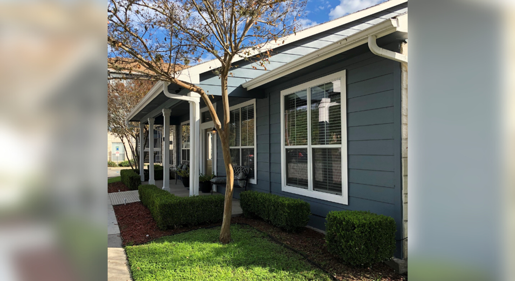 a house with a porch and a tree in front of it
