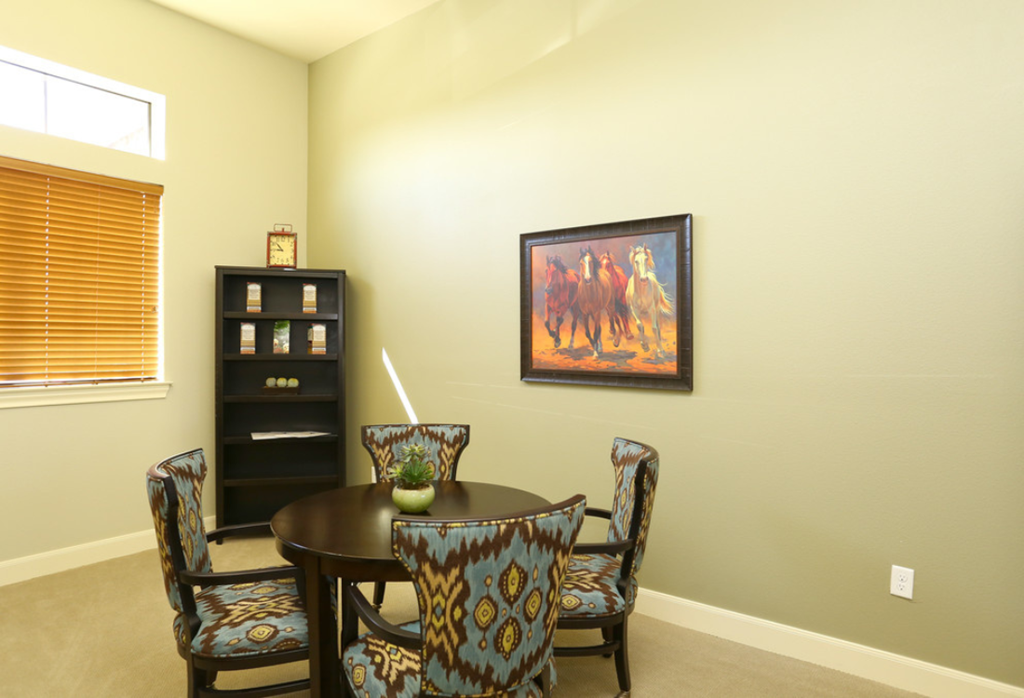 a dining room with a table and chairs and a painting on the wall