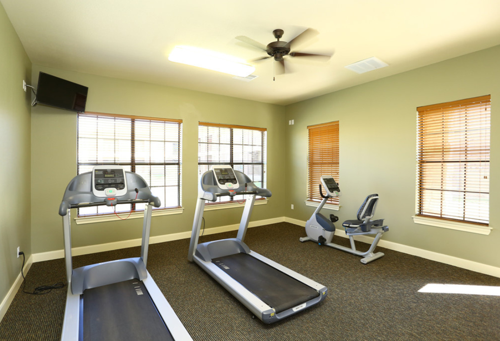 a gym with exercise equipment and a ceiling fan