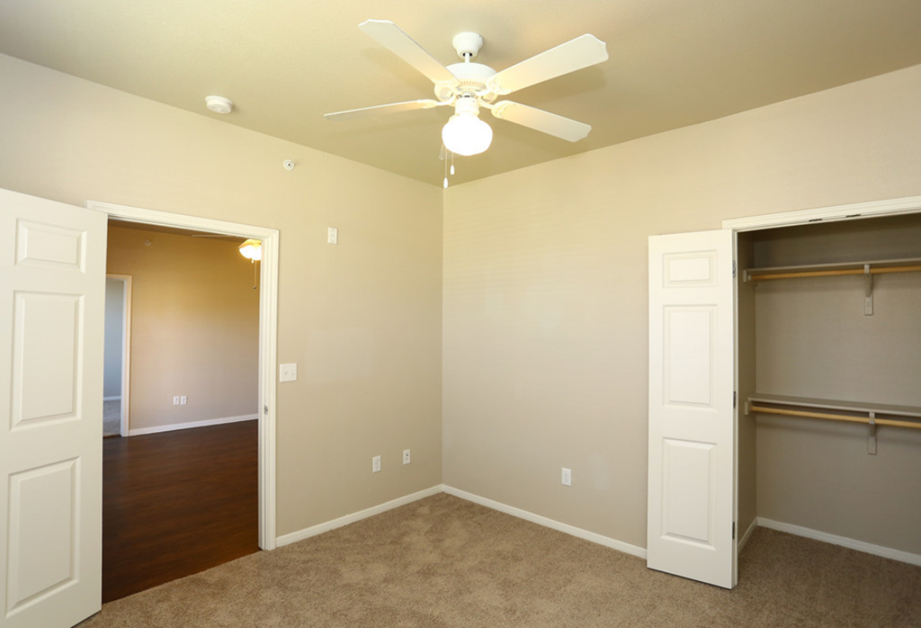 a bedroom with a ceiling fan and a closet