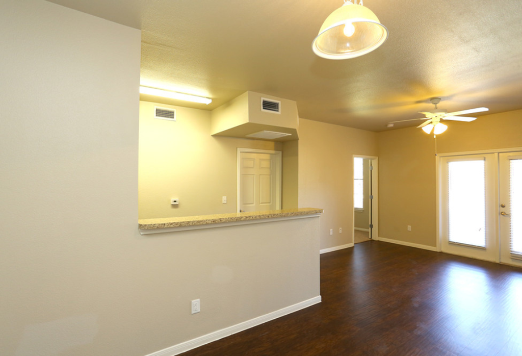 an empty living room with a counter and a ceiling fan