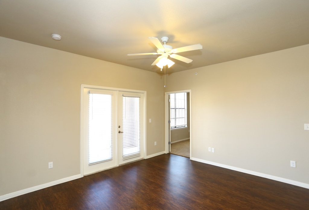 an empty living room with wood floors and a ceiling fan