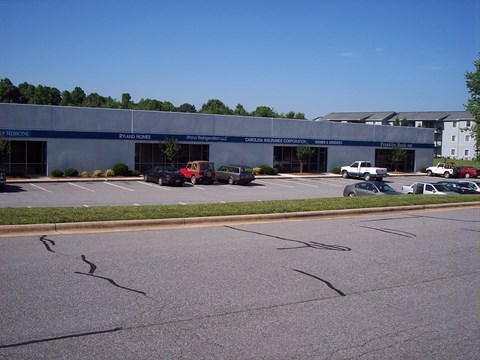 an empty parking lot with cars in front of a building