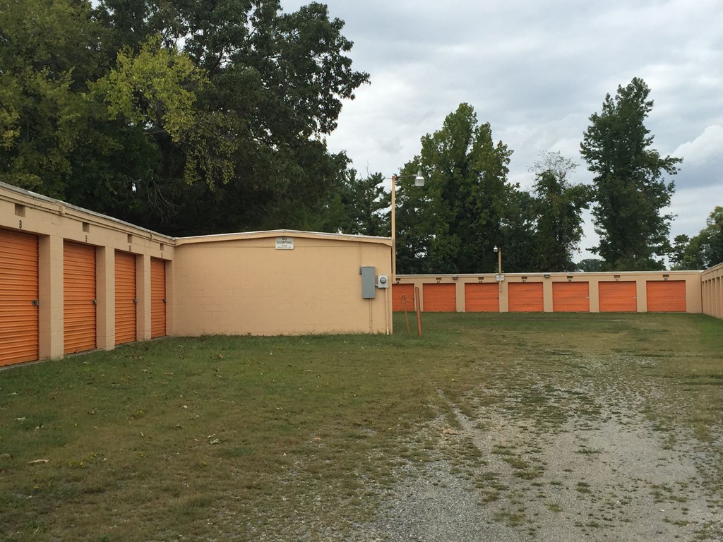 a building with orange doors and a grass field and trees
