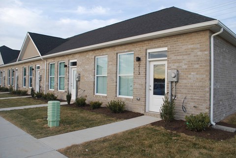 the front of a brick building with a sidewalk and grass