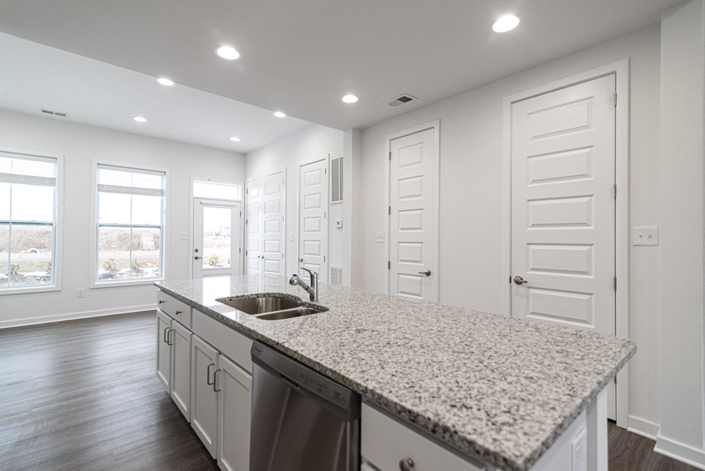an empty kitchen with a granite counter top and a sink