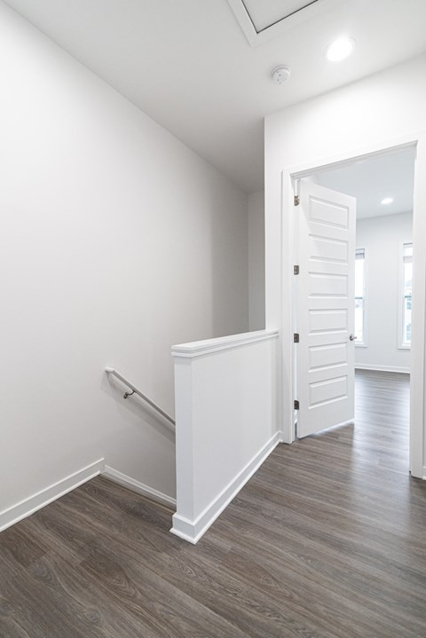 an empty room with white walls and a white door and a staircase