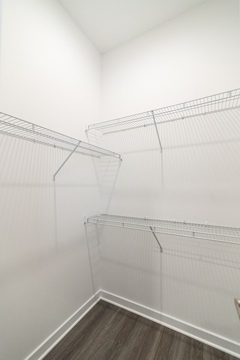 room with white walls and a white closet with metal shelves