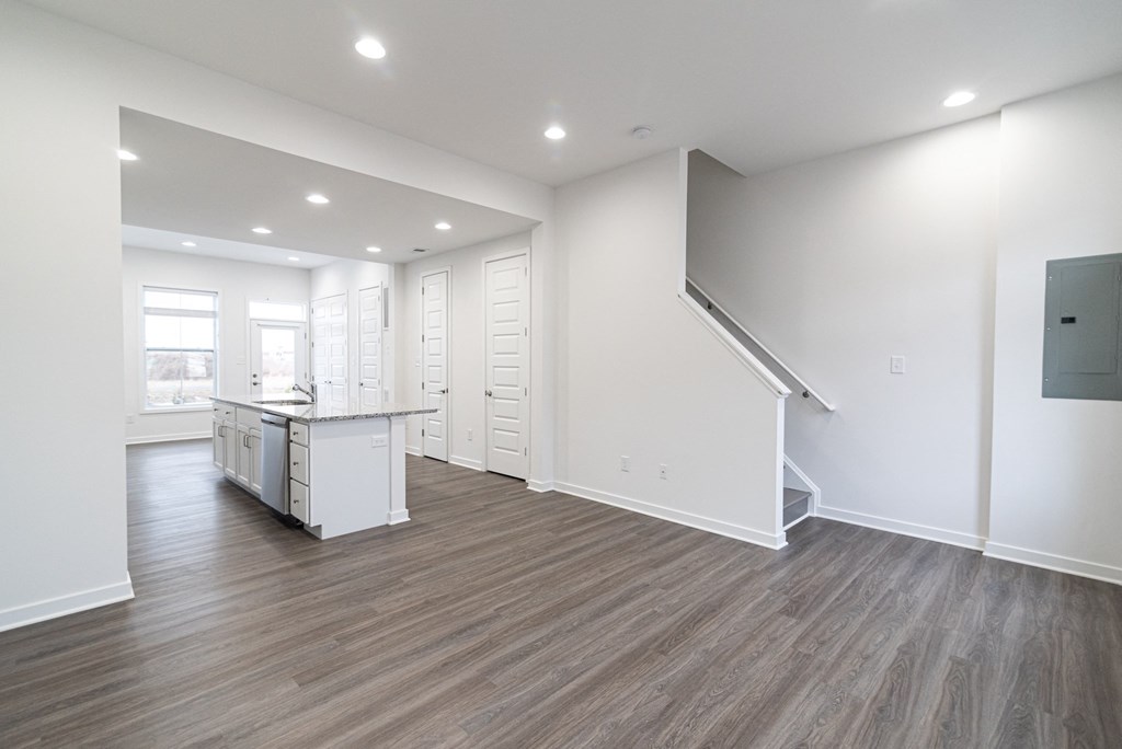 a kitchen and living room with white walls and wood flooring