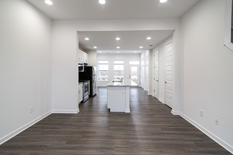 a kitchen and living room with white walls and wood flooring