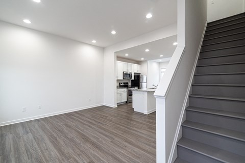 a living room with stairs and a kitchen in a house