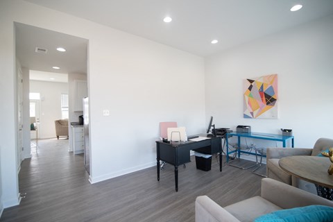 a living room with white walls and a desk with a computer