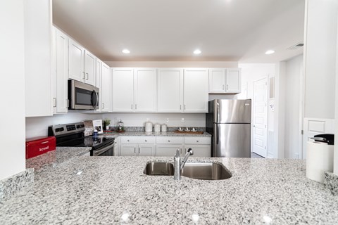 a kitchen with granite counter tops and white cabinets